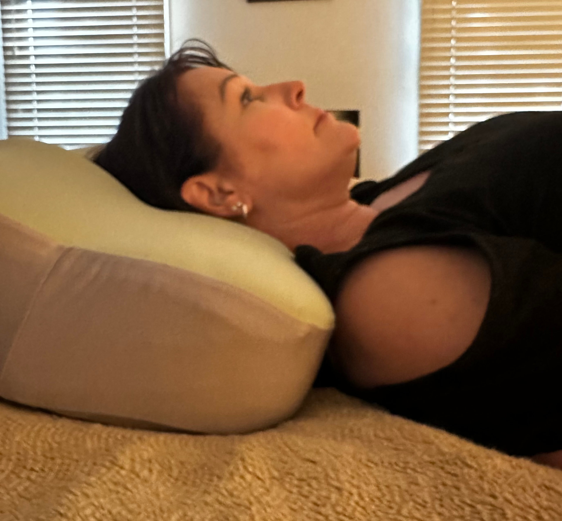 The same woman lying on the same pillow with Crown Lift inside — the pillow holds its loft and her head rests higher.